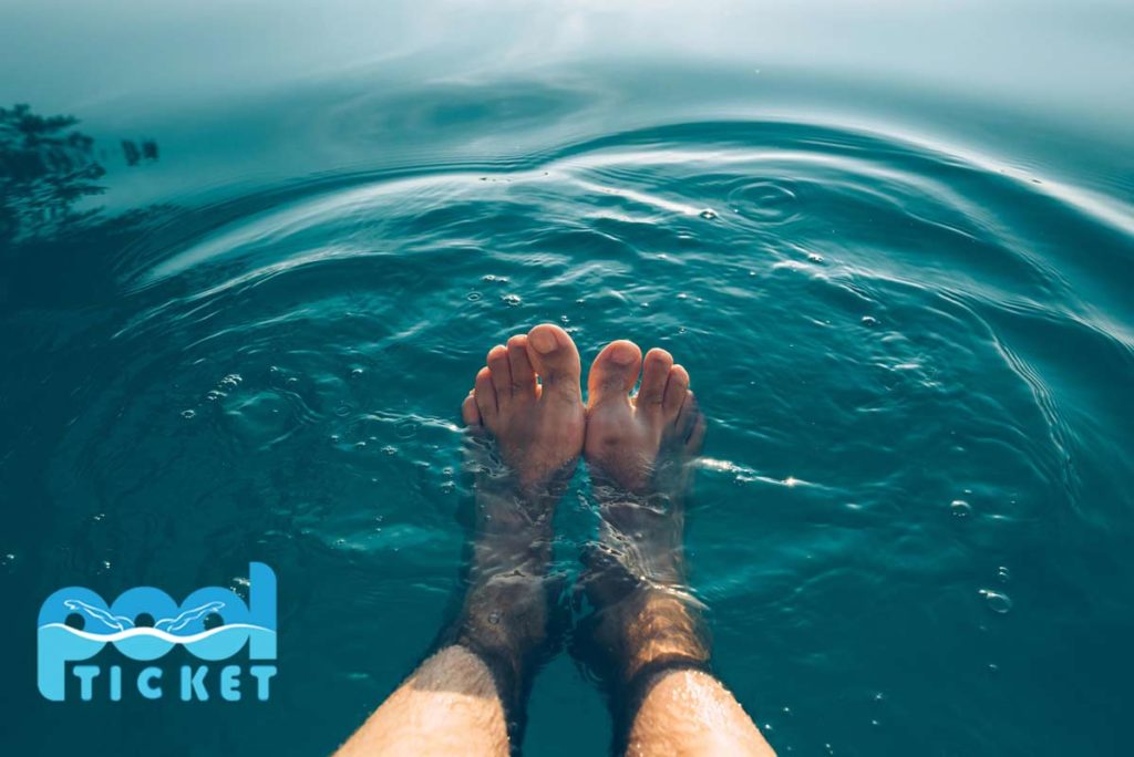 male feet in outdoor swimming pool keeping pool clean